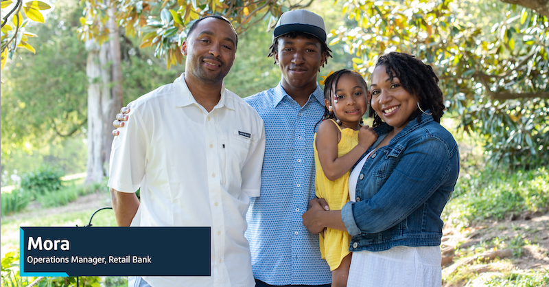 Capital One associate Mora, Operations Manager, Retail Bank, stands outside with her family, holding her daughter